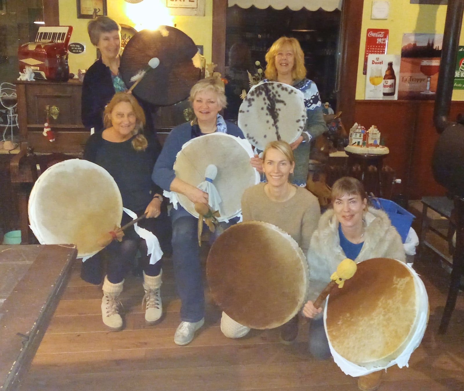 Deelnemers houden hun zelfgemaakte sjamanendrums omhoog aan het eind van de workshopdag