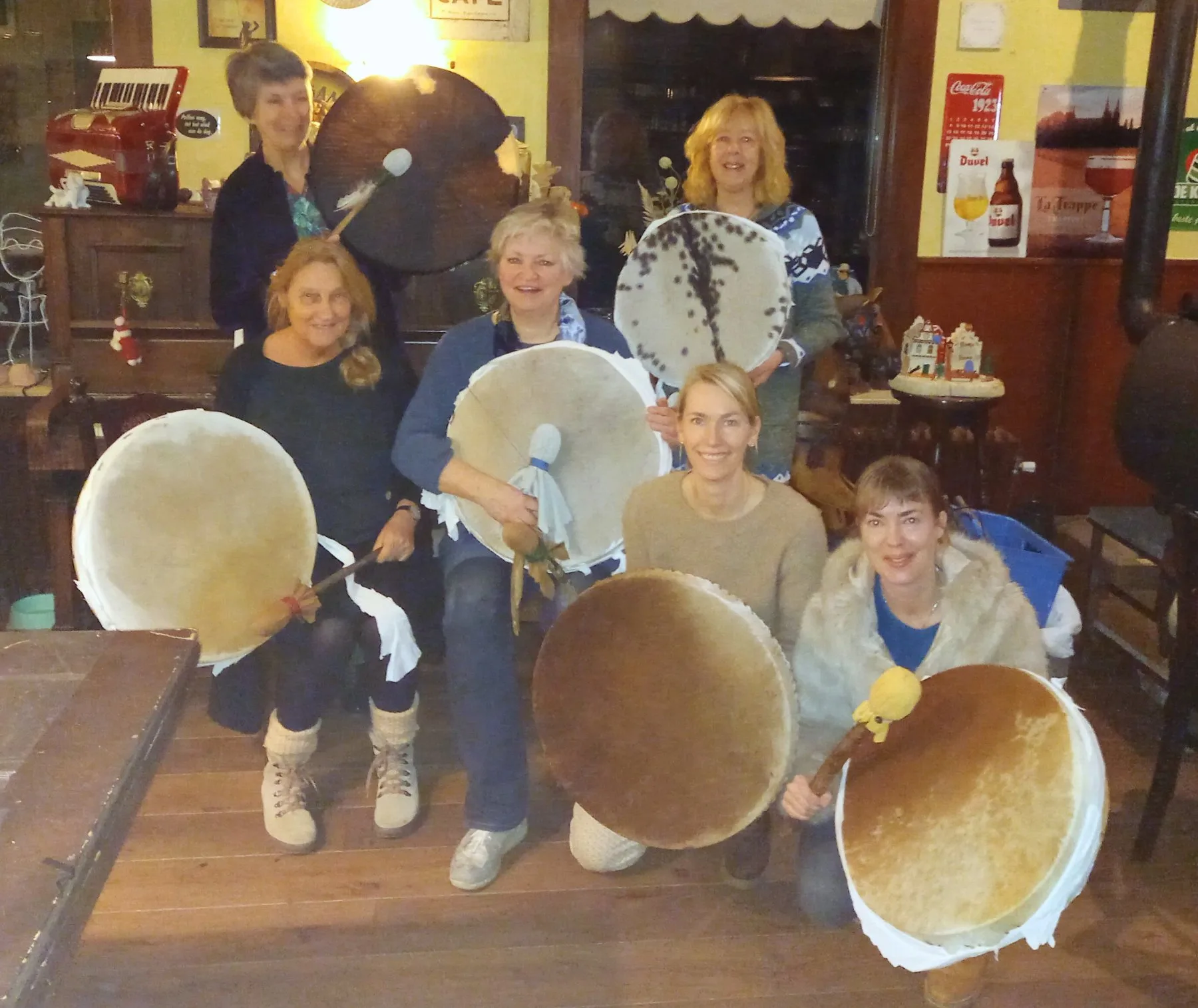 Deelnemers houden hun zelfgemaakte sjamanendrums omhoog aan het eind van de workshopdag