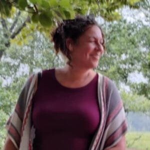 Oesiana lacht met een djembe onder de bomen